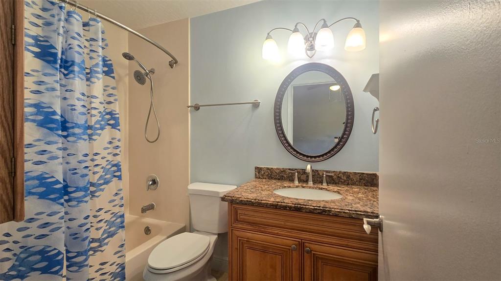 7667 North Wickham Road, Unit 522 Melbourne, FL 32940 - Photo 18 of 25 a bathroom with a granite countertop sink toilet a mirror and shower curtain