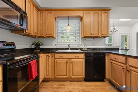 a kitchen with granite countertop a stove top oven a sink dishwasher a dining table and chairs with wooden floor