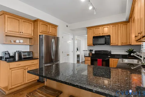 a kitchen with stainless steel appliances granite countertop a refrigerator a stove top oven a sink and dishwasher