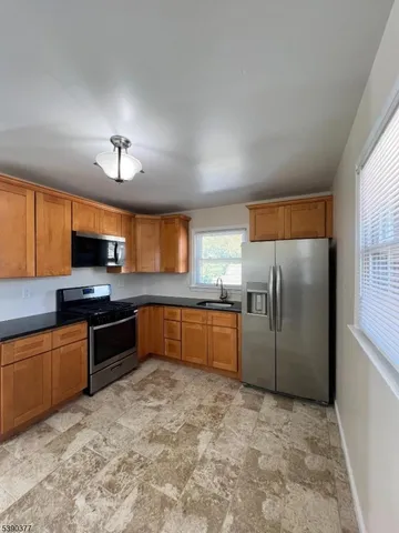 a kitchen with stainless steel appliances granite countertop a refrigerator a stove a sink and a microwave