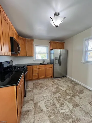 a kitchen with stainless steel appliances granite countertop a stove a sink dishwasher a refrigerator and cabinets with wooden floor