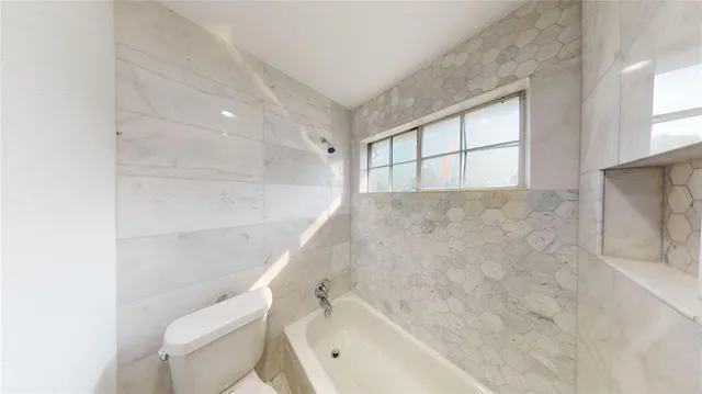 a bathroom with a bathtub toilet and window