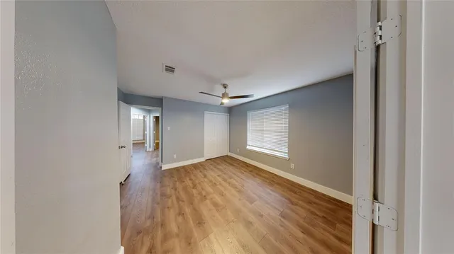 a view of an empty room with wooden floor and a window