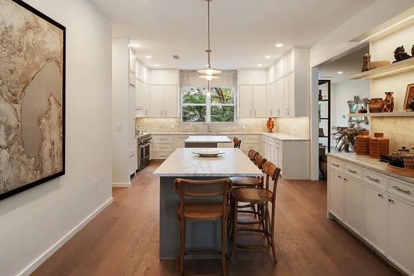 a kitchen with stainless steel appliances a dining table chairs and wooden floor