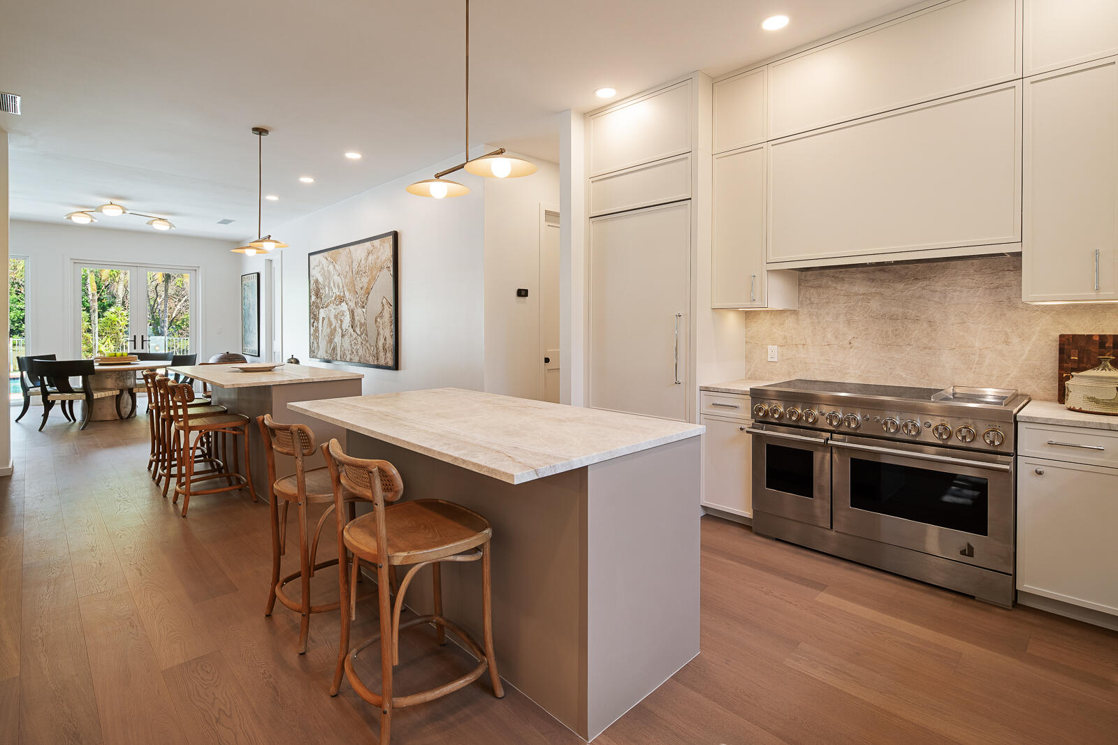 6371 Southwest 87th Terrace Pinecrest, FL 33156 - Photo 10 of 16 a kitchen with stainless steel appliances granite countertop a stove a refrigerator a kitchen island a dining table and chairs with wooden floor