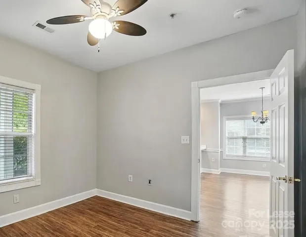 a view of empty room with wooden floor and fan