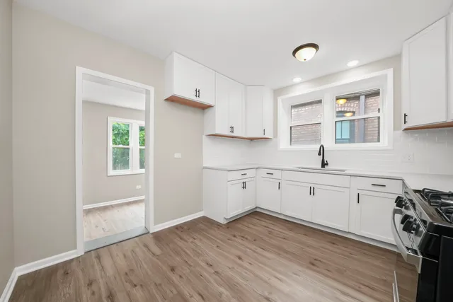 a kitchen with wooden floors and white cabinets