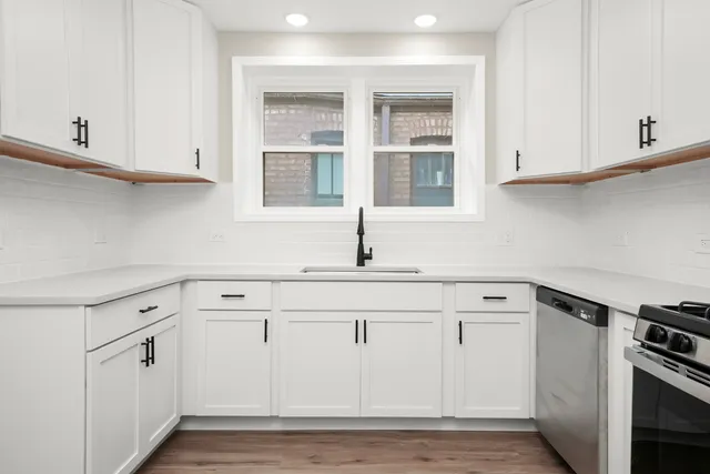 a kitchen with white cabinets and sink
