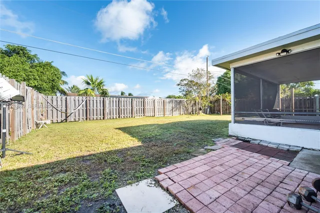 a view of a backyard with brick wall and potted plants