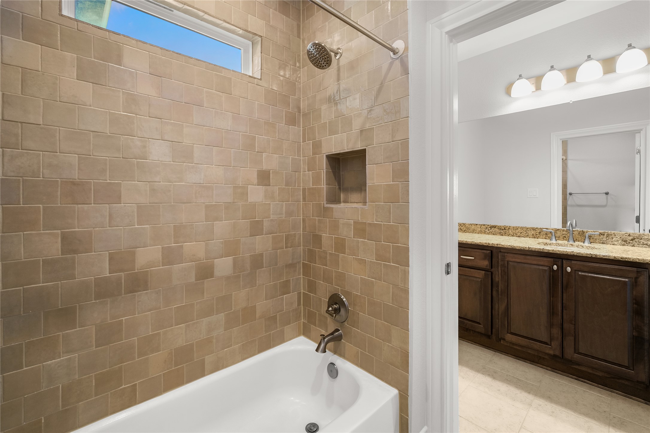 955 Inka Road Salado, TX 76571 - Photo 19 of 39 Tiled walls enclose the soaking tub adjacent to a vanity with stone counters.