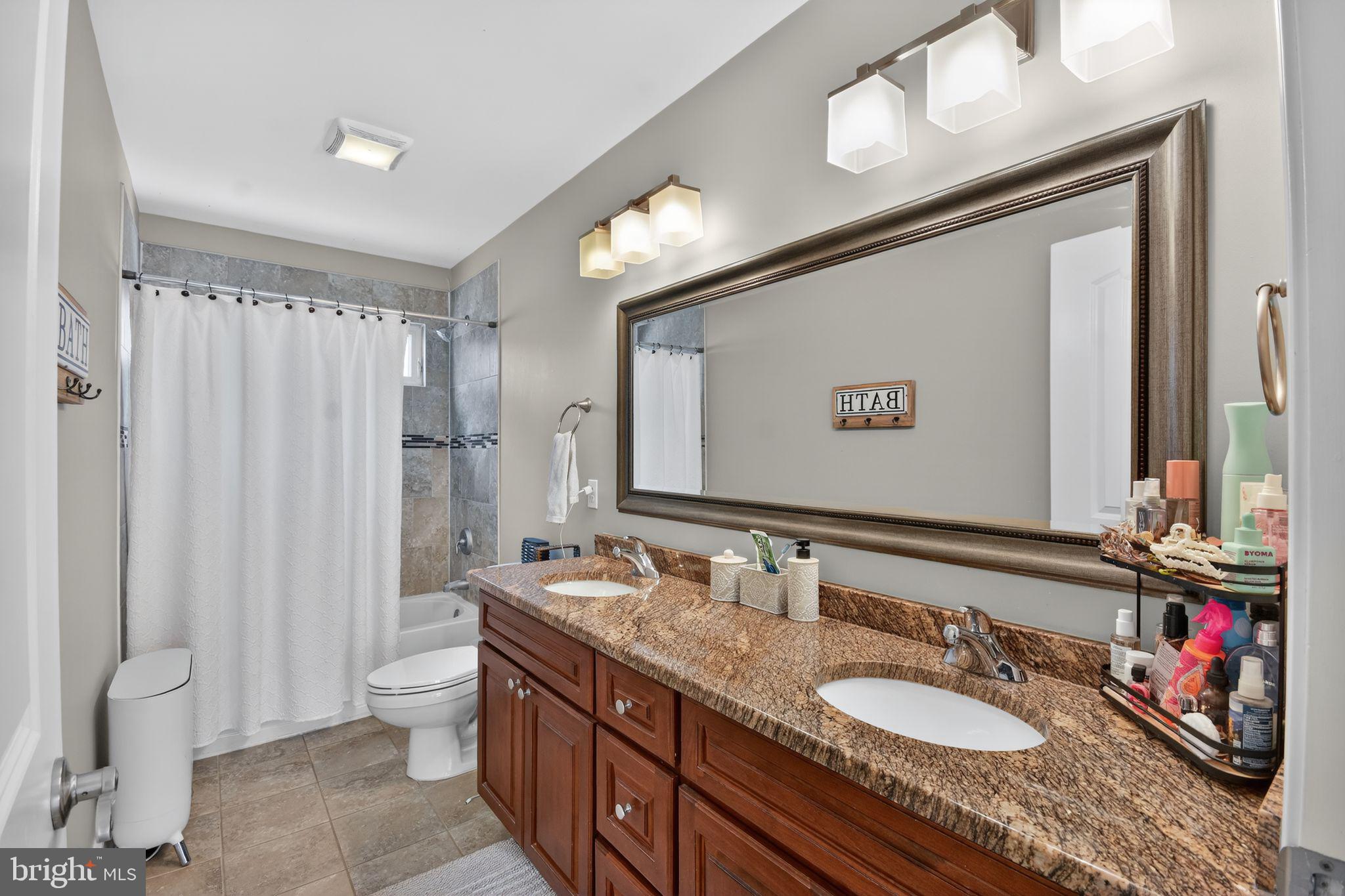 95 Savannah Road Manchester Township, NJ 08757 - Photo 27 of 37 a bathroom with double vanity sinks a toilet a mirror and shower