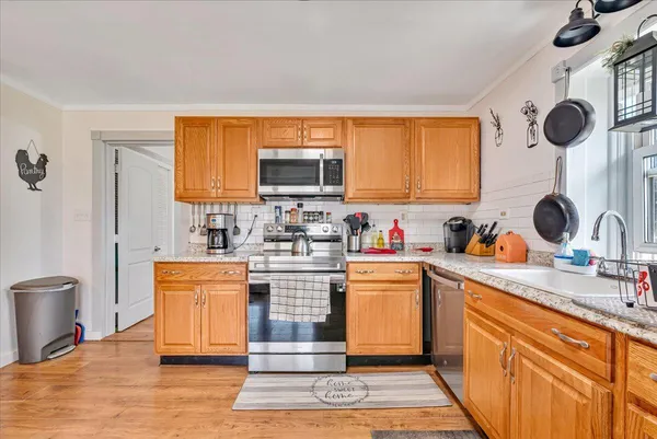 a kitchen with stainless steel appliances kitchen island granite countertop a stove top oven a sink a dining table and chairs with wooden floor