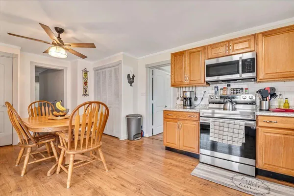 a kitchen with stainless steel appliances granite countertop a refrigerator a stove a sink dishwasher and white cabinets with wooden floor