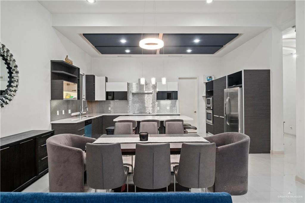 206 North Mockingbird Avenue Mission, TX 78572 - Photo 11 of 22 a kitchen with stainless steel appliances granite countertop a stove a refrigerator a sink a refrigerator white cabinets and couches with wooden floor