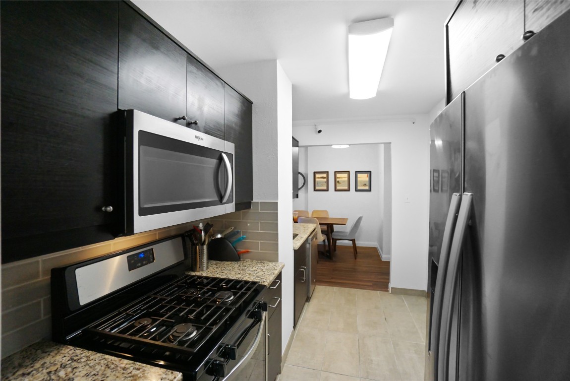 1212 Guadalupe Street, Unit 402 Austin, TX 78701 - Photo 8 of 20 a kitchen with stainless steel appliances a refrigerator and a stove top oven