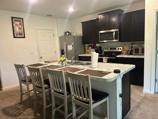 a kitchen with a stove a microwave a dining table and chairs