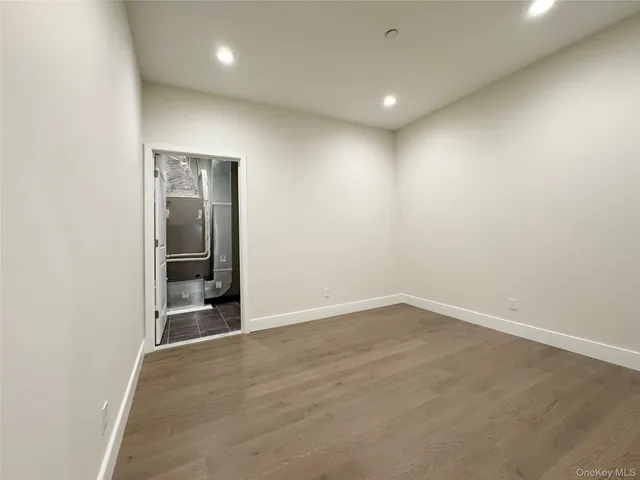 an empty room with wooden floor and a hallway
