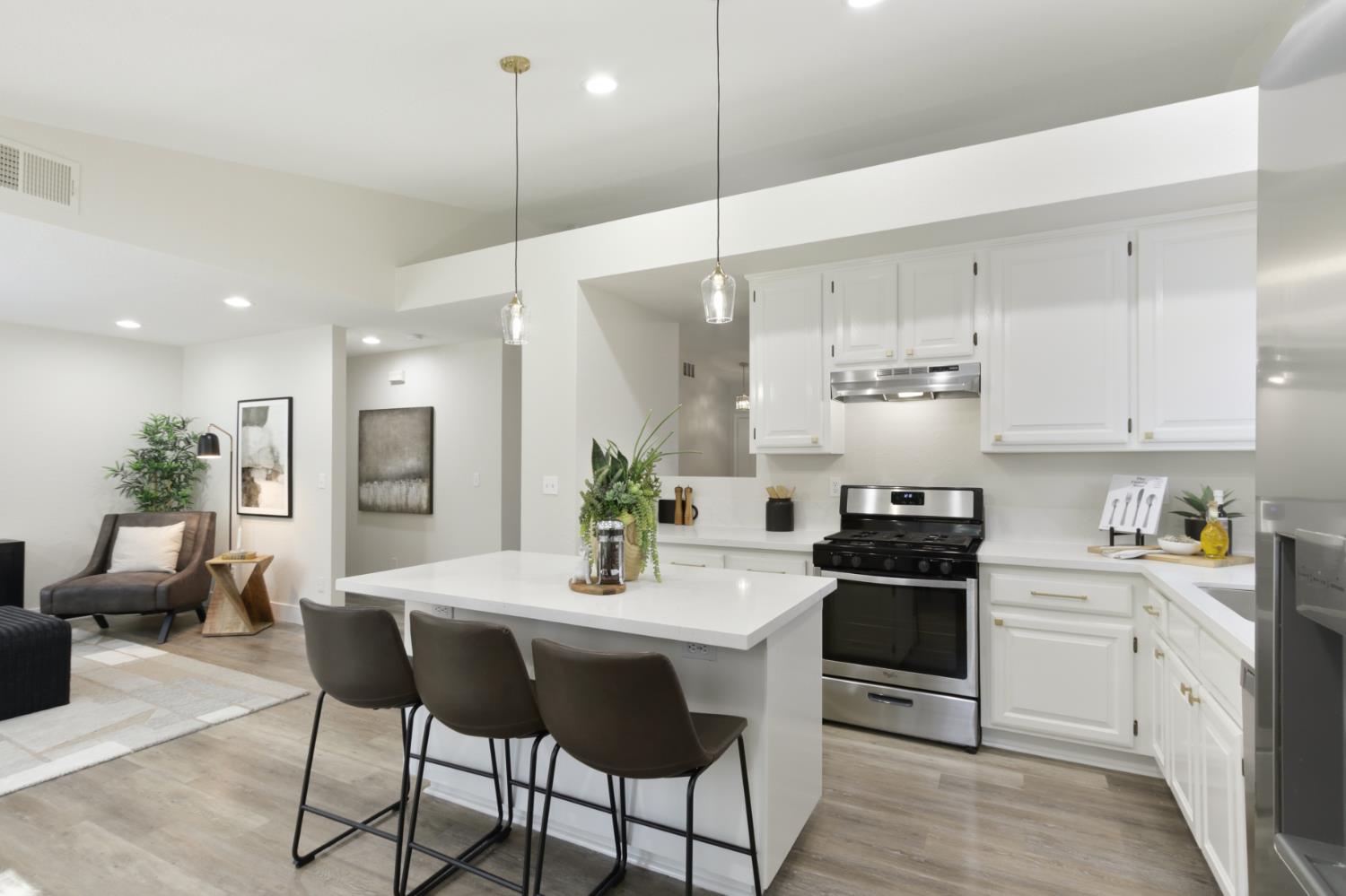 4711 Stuart Street Rocklin, CA 95765 - Photo 16 of 48 a kitchen with stainless steel appliances kitchen island granite countertop a stove a sink a dining table and chairs with wooden floor