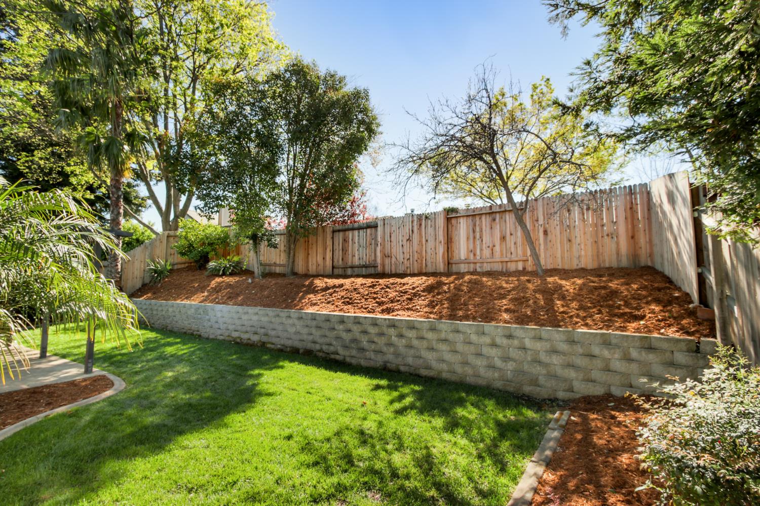 4711 Stuart Street Rocklin, CA 95765 - Photo 45 of 48 a view of a backyard with a large tree and wooden fence