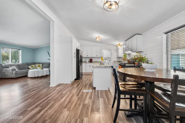 a kitchen with stainless steel appliances granite countertop a table chairs sink and cabinets