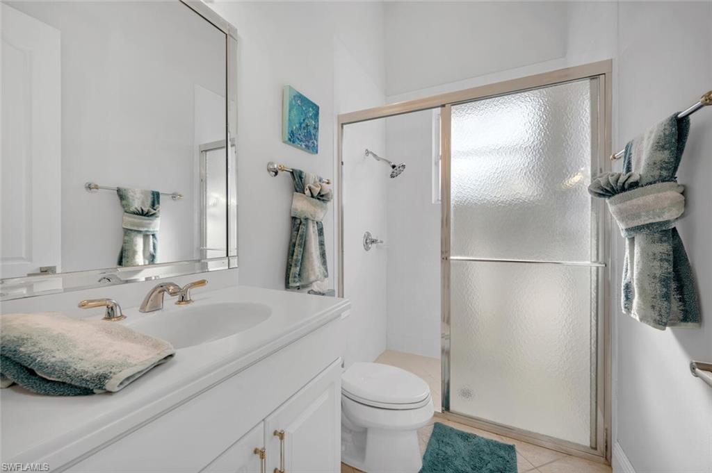 400 Terracina Way Naples, FL 34119 - Photo 17 of 29 Bathroom featuring tile patterned floors, vanity, toilet, and an enclosed shower