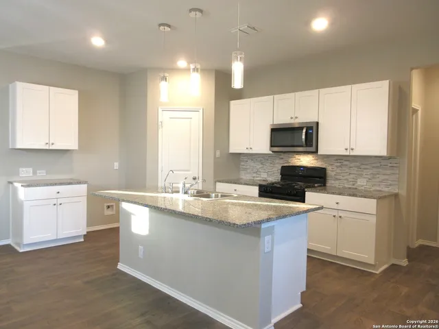 a kitchen with a sink a stove a microwave a counter top space and cabinets