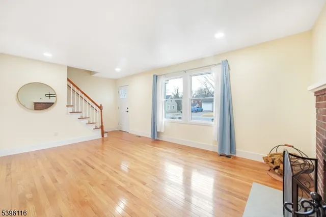 a view of an empty room with wooden floor fireplace and a window