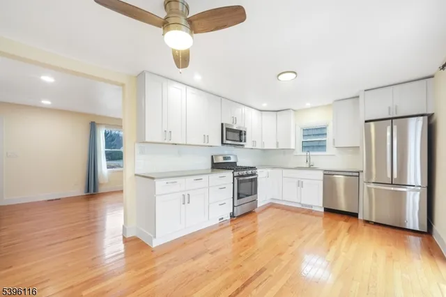 a kitchen with granite countertop a stove a sink and white cabinets