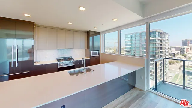 a large kitchen with stainless steel appliances a large counter top a stove and a refrigerator