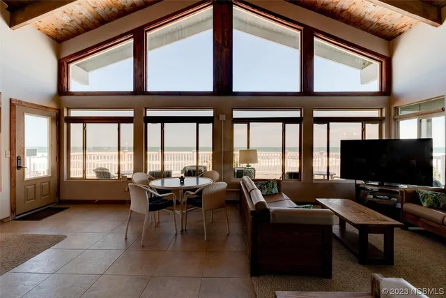 a living room with furniture large windows and flat screen tv