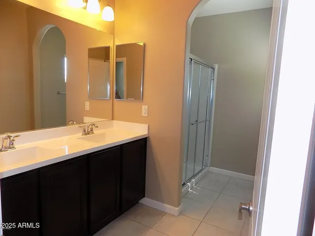 a view of a hallway with wooden floor and a bathroom
