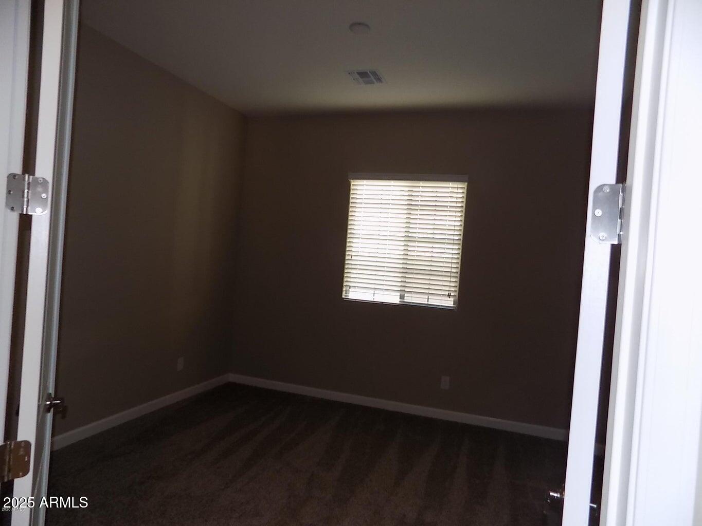 1367 South Country Club Drive, Unit 1076 Mesa, AZ 85210 - Photo 9 of 33 an empty room with wooden floor and windows