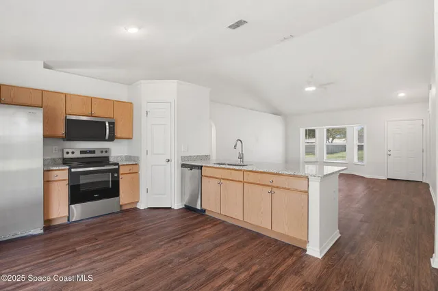 a large kitchen with stainless steel appliances granite countertop a stove a sink and a refrigerator