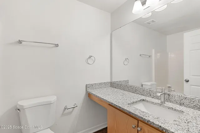 a bathroom with a granite countertop sink a mirror and a toilet