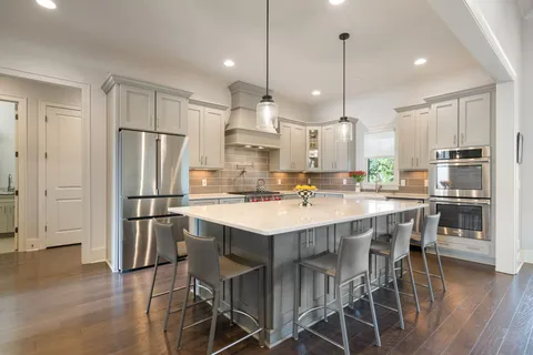 a kitchen with stainless steel appliances granite countertop a sink a stove a refrigerator and island with wooden floor