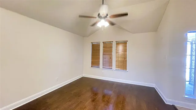 a view of a room with wooden floor a ceiling fan and a window