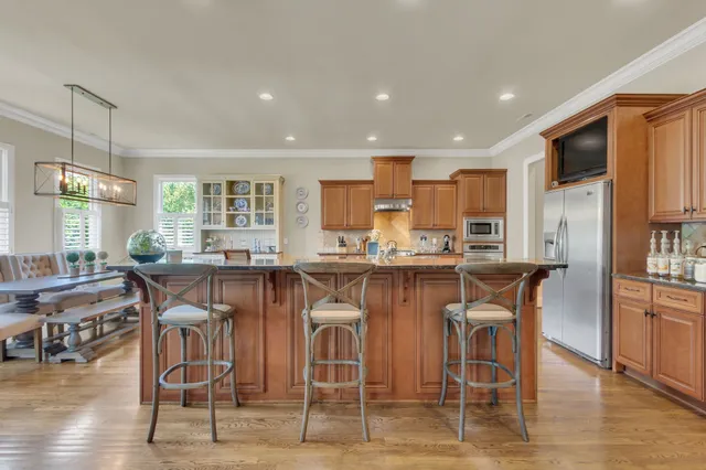 a kitchen with stainless steel appliances granite countertop a sink a stove and a wooden floors