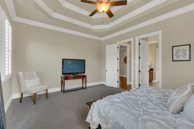 a bedroom with a bed a chair and potted plant on the dresser