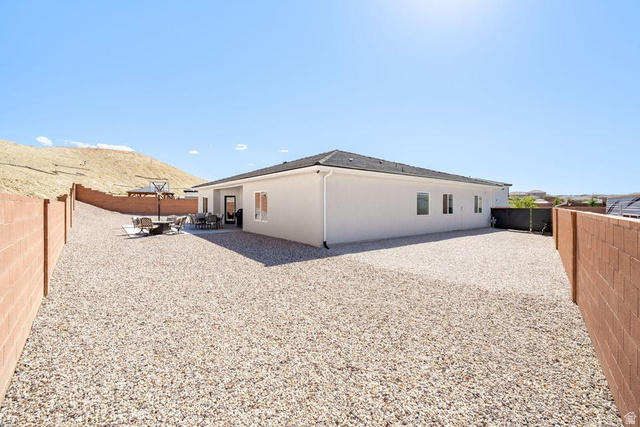 5963 Flattop Drive St. George, UT 84790 - Photo 40 of 45 Expansive gravel backyard featuring a stucco exterior, multiple windows, a rear patio, and durable block wall fencing