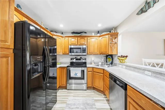 a kitchen with stainless steel appliances kitchen island granite countertop a dining table chairs and a refrigerator