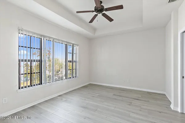a view of an empty room with a window and wooden floor