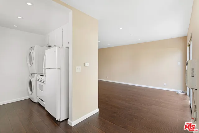 a view of a livingroom with wooden floor and a refrigerator