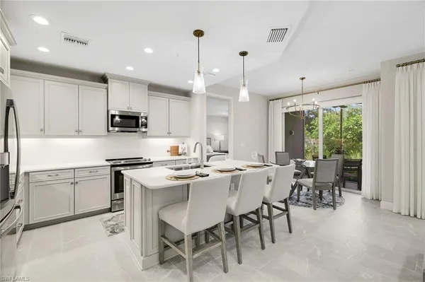 a kitchen with stainless steel appliances granite countertop a stove a sink a refrigerator a dining table and chairs