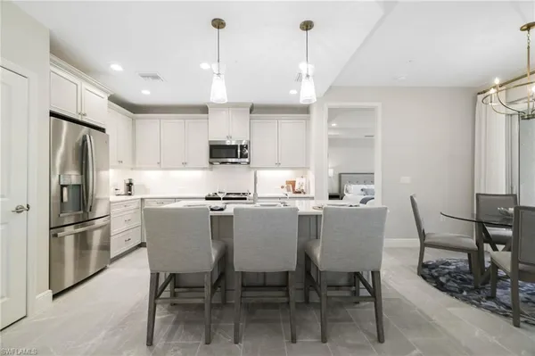 a kitchen with stainless steel appliances a dining table chairs refrigerator and sink