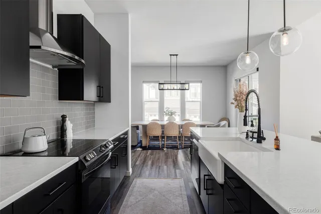 a very nice looking kitchen with granite countertop a stove a sink a dining table and chairs