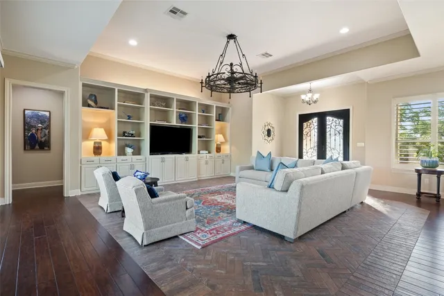 a living room with furniture a flat screen tv and a chandelier