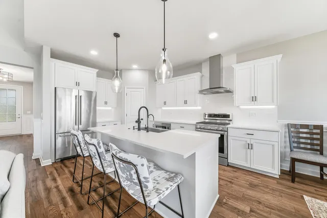 a kitchen with stainless steel appliances kitchen island granite countertop a sink a stove a dining table and chairs