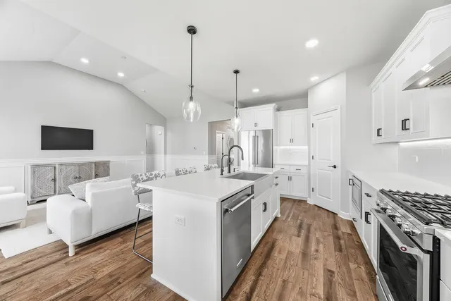 a large kitchen with kitchen island a white counter space a sink stainless steel appliances and cabinets