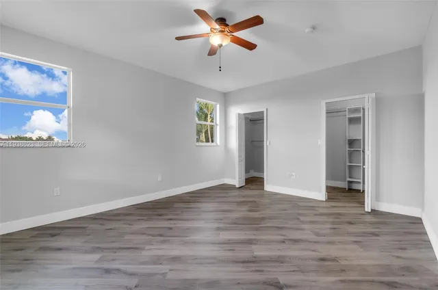 a view of an empty room with a window and wooden floor