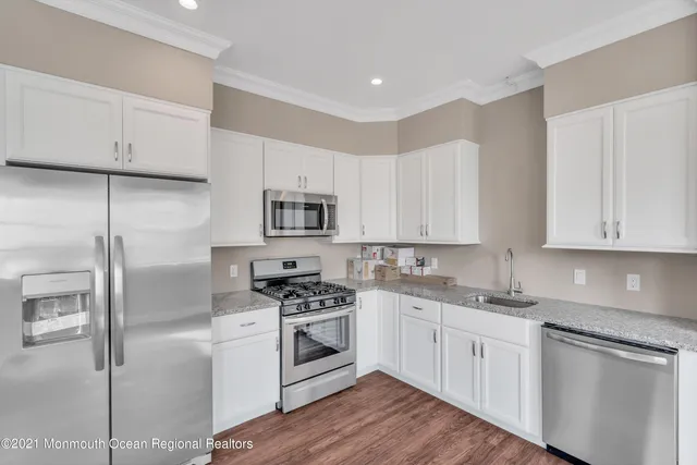 a kitchen with stainless steel appliances a dining table chairs sink and cabinets